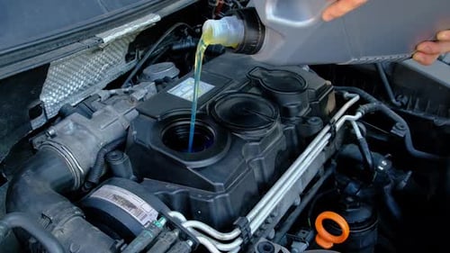 Yellow Oil Being Poured Into Car Engine