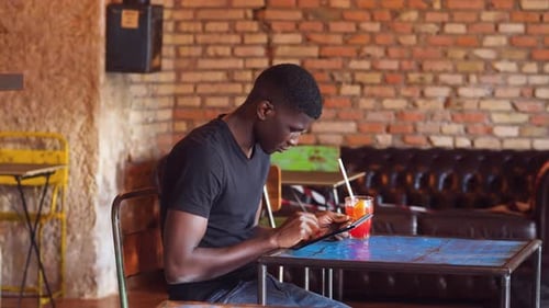technology, youth - black man at pub scrolls the keyboard of the tablet