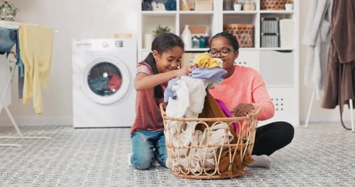 A Smiling Mature Woman with Glasses is Sitting on the Bathroom Floor with a Basket Full of Laundry
