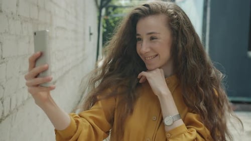 Woman Smiles During Video Call in Urban Setting