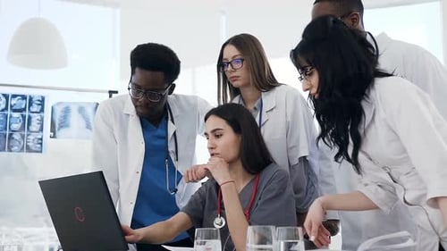 Medical Team Collaborating Around Laptop in Office