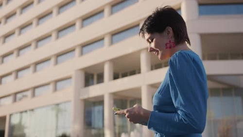 Woman Using Smartphone Near Modern Urban Building