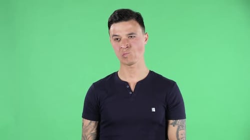 Porträt eines gutaussehenden jungen Mannes, der gerade und konzentriert aussieht und über etwas nachdenkt.
grün
