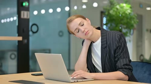 Tired Woman Massaging Neck at Laptop in Office