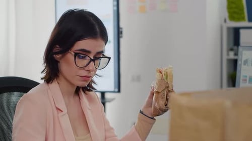 Young Adult Woman Eating Lunch at Desk in Office
