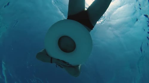 Woman Swimming with Swim Ring Underwater in Blue Water
