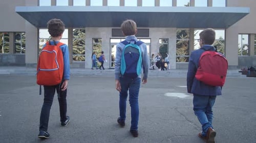 Three Schoolboys Walking To School Doors