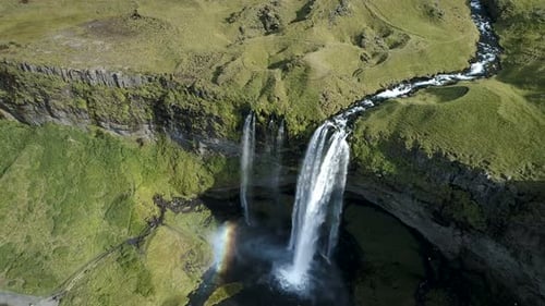 Aerial View of Waterfall Cascading Through Green Landscape