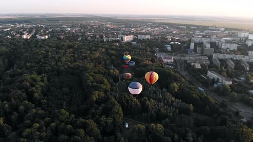 Beautiful balloons fly over the forest, park, city.