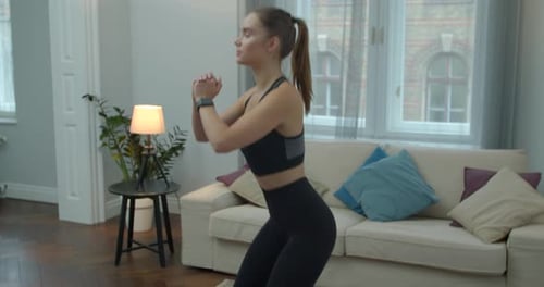 Athletic Woman Doing Squats in Modern Apartment