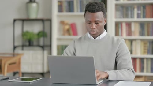 Man Typing on Laptop Massaging Temples