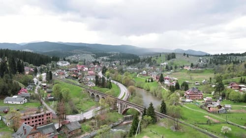 Mountain village with old railway viaduct bridge over river.