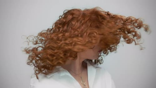 Stylish Woman with Copper Red Curls Shakes Head