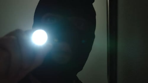 Person in Black Mask with Flashlight at Night