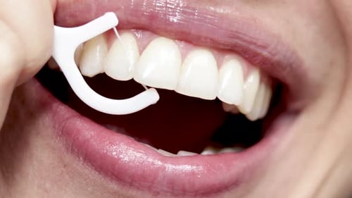 gros plan vidéo 4k femme bouche souriante et passant la soie dentaire avec un cure-dent en plastique blanc. beau