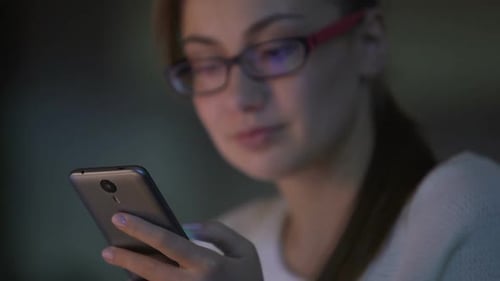 Woman Using Smartphone in Dark Room at Night