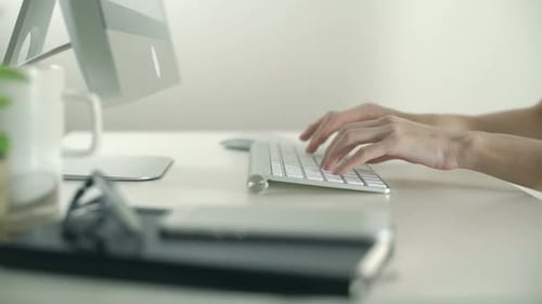 Hands Typing on Keyboard at Office Desk