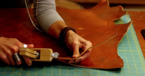 Close-up of craftswoman cutting leather