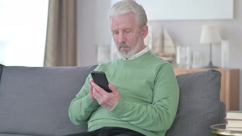 Senior Man Using Smartphone While Sitting on Couch