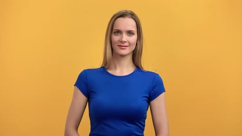 Retrato de una hermosa joven rubia en camiseta azul sonriendo posando aislada en Orange Studio
