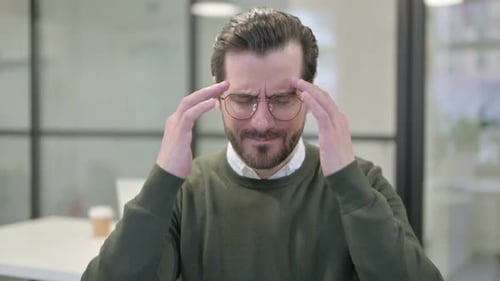 Man Rubs Temples Indicating Headache Pain Indoors