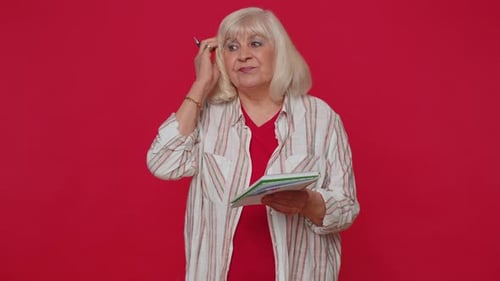 Senior Woman Thinking and Writing in Notepad