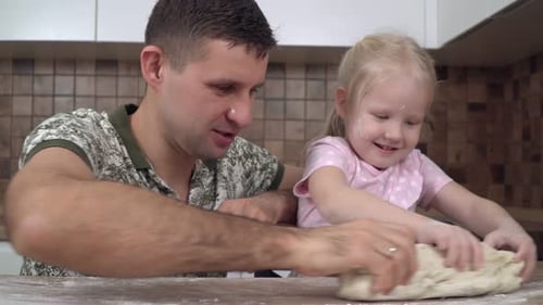 Father and Child Kneading Dough in Kitchen