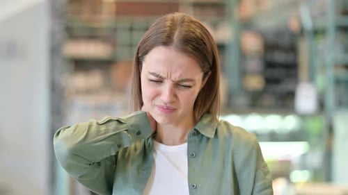 Young Woman Massaging Stiff Neck Indoors