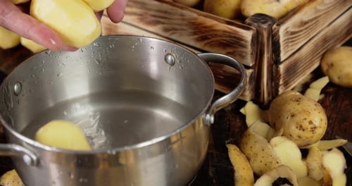 Potato Falls From Men's Hands in a Pot of Water