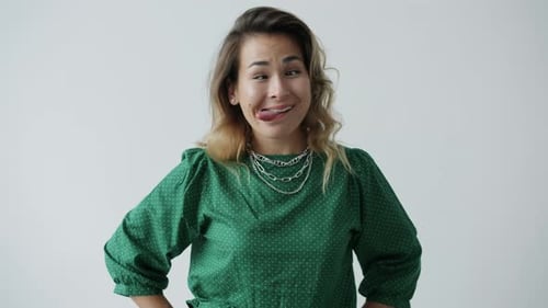 Retrato de uma jovem engraçada fazendo expressões faciais divertidas e fazendo caretas na cor branca