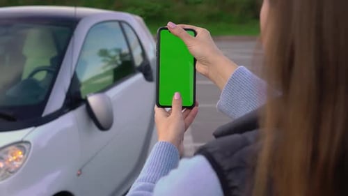 Girl with Mobile Green Screen Takes Photo in Parking