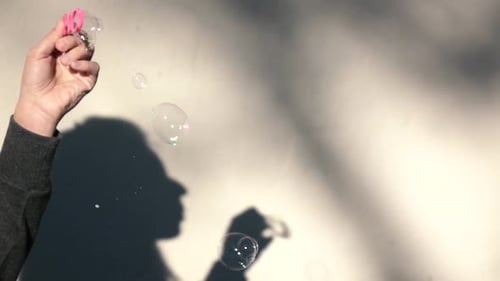 Hand Blowing Soap Bubbles with Shadow on Wall