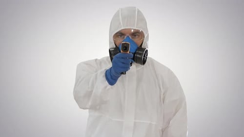Male Doctor in Protective Suit Holding an Digital Infrared Thermometer Pointing with It To Camera on