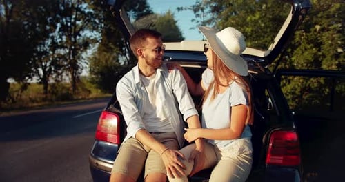 Happy Couple Relaxing on Car During Summer Road Trip
