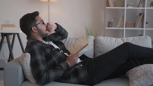 Man Reading Book on Couch at Home