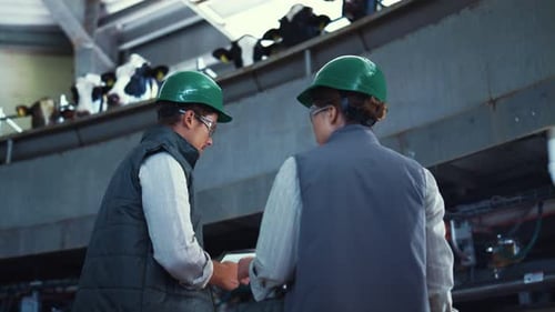 Spécialistes de bétail travaillant des machines à traire automatiques avec l'ordinateur de tablette