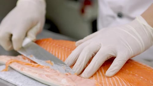Person filleting salmon with knife close up shot