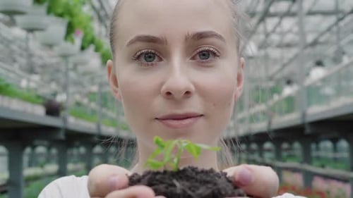 Close-up Face of Beautiful Young Woman Holding Green Plant in Hands. Portrait of Gorgeous Caucasian