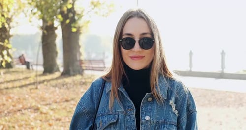 Portrait of Young Attractive Female Who Smiling and Looking at the Camera on Autumn Park. Cheerfully