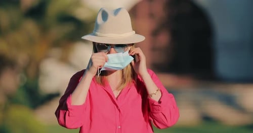Woman Puts on Surgical Mask Outdoors
