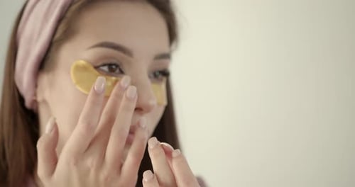 Woman Applies Golden Eye Patches for Skincare