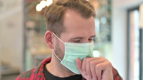Man Wearing Face Mask Coughing Into Elbow