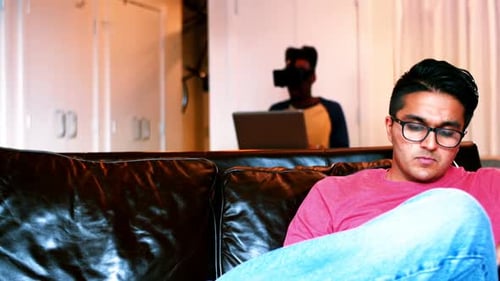 Young Adults Using VR Headset and Laptop at Home