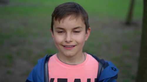 Feliz adolescente entre paréntesis mirando la cámara al aire libre. Chico guapo sonriendo en el parque