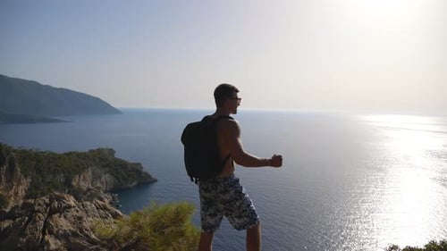 Male Hiker Standing on Peak and Victoriously Raising Arm Rejoicing Success