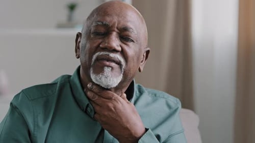 Mature Adult Touching Neck Indoors