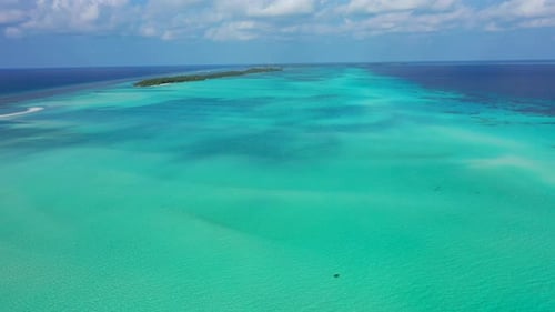 Daytime birds eye travel shot of a white sandy paradise beach and aqua blue water background in vibr