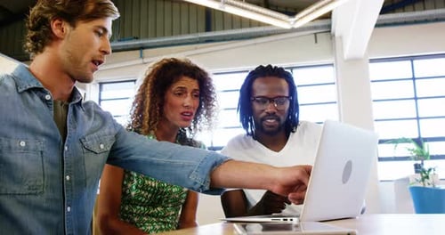 Cheerful Colleagues Collaborating on Laptop in Modern Office