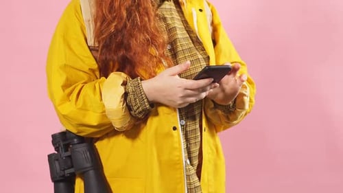 Woman in Yellow Raincoat Using Smartphone