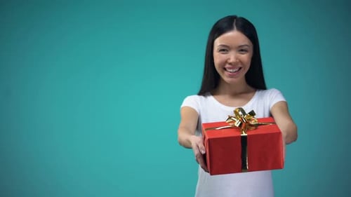 Woman Presents Gift Box in Front of Blue Backdrop